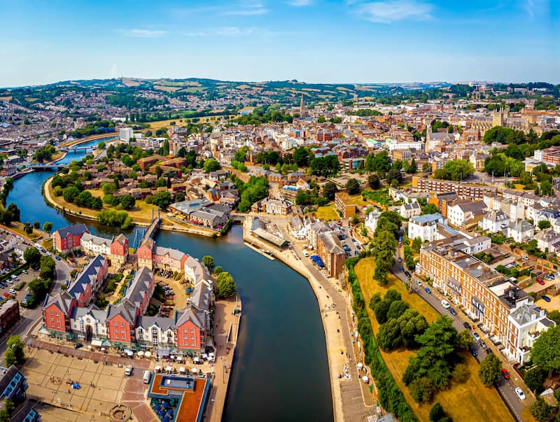 Arial image of Exeter Quay. Trees and buildings in Exeter, Devon line each side of the river, it is a sunny day and in the distance in the far right is Exeter Cathedral.